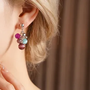 Colorful cat eye stone tassel earrings with silver studs on elegant woman model