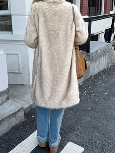 Manteau élégant en fausse fourrure beige à manches longues porté avec un jean en ville