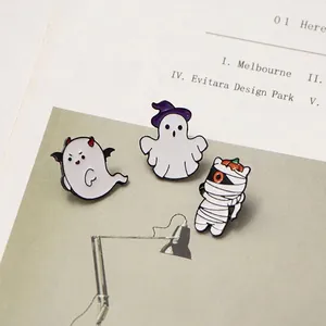 Three Halloween enamel pins featuring ghosts and pumpkin on a stylish magazine background