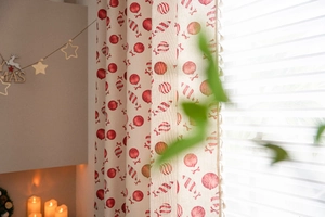 Detail of beige holiday curtain with red candy patterns and festive tassel fringe edge