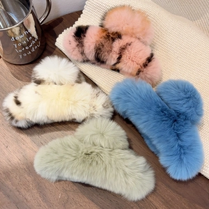 Macro detail of plush faux rabbit fur hair claws in assorted winter colors on a soft knit