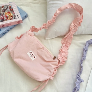 Detailed close-up of pink pleated canvas bag with stylish ruffled shoulder strap design