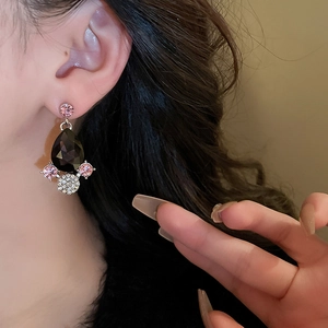 Close-up of teardrop black gemstone earrings with pink accent stones on model