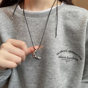 Detailed view of croissant-shaped silver pendant on black adjustable cord necklace