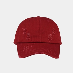 Detail of distressed ripped texture and vintage finish on burgundy cotton baseball cap