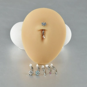 Macro shot of 16G titanium belly rings with zircon and opal drop charms on a silicone model