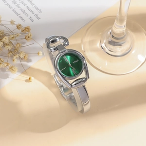 Close-up of elegant women's watch featuring a green sunburst dial and silver steel band