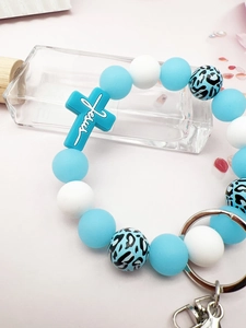 Detailed macro view of silicone beads and a blue cross charm with Jesus inscription