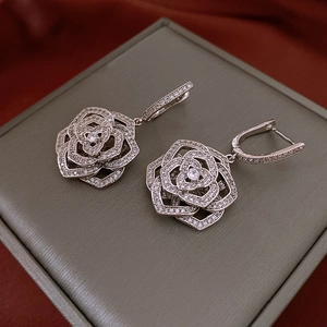 Detailed close-up of hollow camellia flower earrings with micro-set cubic zirconia crystals