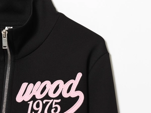 Detail of pink wood 1975 embroidery on black zip-up sweatshirt with silver metal zipper