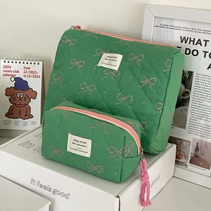 Detailed set of green quilted cosmetic bags with pink bow pattern and smooth zippers