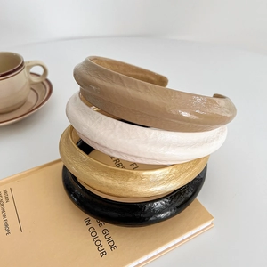 Padded faux leather headbands set in khaki, beige, and black on minimalist aesthetic desk