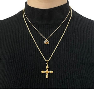 Layered stainless steel necklace with tiger eye stone and cross pendant on a model