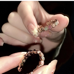 Detailed close-up of rainbow zircon stacked rings in rose gold on model's fingers