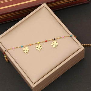 Détail d'un bracelet trèfle doré avec perles émaillées colorées sur un écrin à bijoux