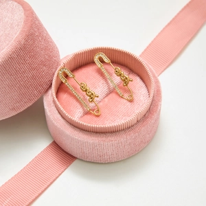 Vue rapprochée des boucles d'oreilles trombone dorées LOVE avec strass et boîte rose
