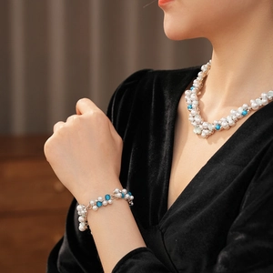 Dettaglio del set collana e bracciale vintage con perle bianche e blu indossati sul modello