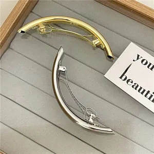 Close-up of sleek gold and silver curved metal hair clips on a velvet jewelry tray