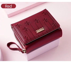 Detail of red faux leather wallet with floral embroidery and golden metal clasp