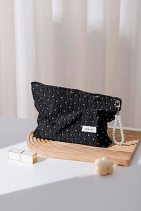 Detailed view of polka dot cosmetic bag with pleated texture and pearl handle chain
