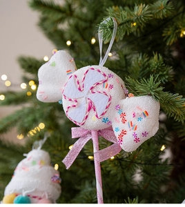 Pink and white candy cane ornament with bow hanging on a decorated Christmas tree
