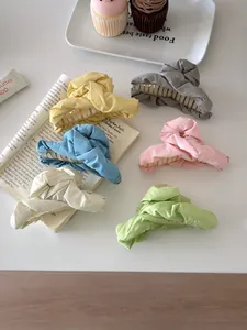 Detail view of colorful pleated fabric hair claws in six pastel shades for women's styling