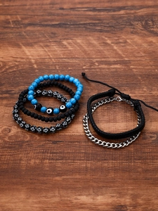 Flat lay of 6-piece beaded evil eye bracelet set on dark wood grain surface