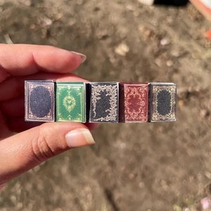 Detail of metal hair clip featuring five colorful miniature books in hand with natural light