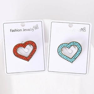 Detail of red and blue beaded heart brooches on display cards with bronze metal base
