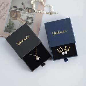 Luxurious drawer jewelry boxes in black and navy with gold pearl necklace and earrings