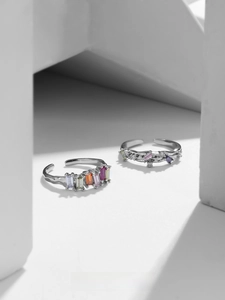 Close-up of irregular silver rings with baguette-cut rainbow stones and fluid texture