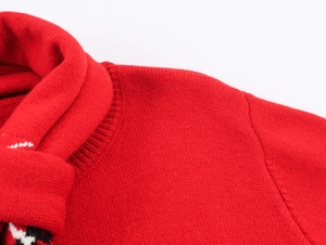 Detail of red knit sweater featuring ribbed crewneck and patterned scarf in soft wool texture
