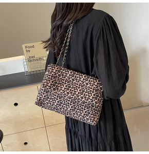 Detail of leopard print tote bag with gold chain strap worn by a model in black dress