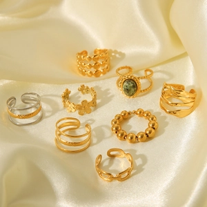 Collection of golden multilayer stackable rings with green stone on silk background