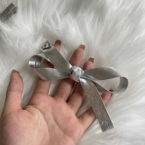 Close-up of silver bow hair clip featuring shiny pink and blue rhinestones on plush background