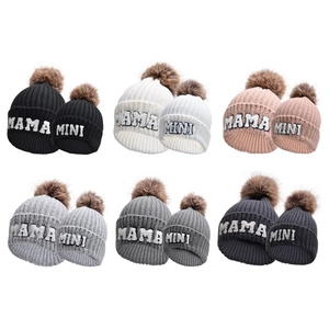 Dettaglio di cappelli in maglia per famiglia multicolore con ricamo MINI MAMA e pompon