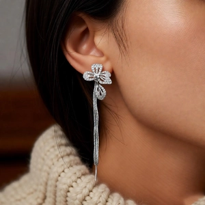 Close-up of elegant flower stud earrings with zircon petals and silver fringe tassels