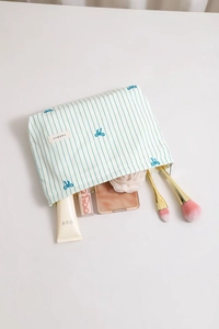 Detailed macro view of striped embroidery bow fabric cosmetic bag and metal zipper