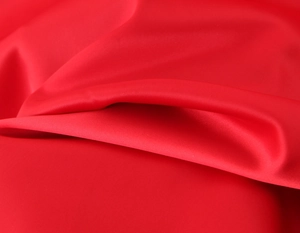 Macro shot of high-quality red satin fabric texture showing smooth glossy finish