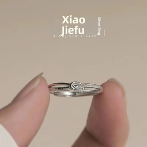 Close-up of a silver knot ring with polished band and micro-paved cubic zirconia details