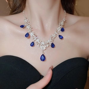 Detailed close-up of a silver necklace featuring blue pear-shaped gemstones and crystals