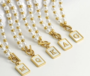Detail of OT buckle pearl necklaces with rectangular gold 26-letter enamel pendants