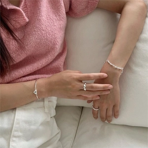 Detail of S925 sterling silver woven bracelet and rings set on model with knit sweater