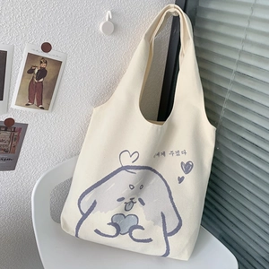 Dettaglio della borsa tote in tela crema con illustrazione di cane su sedia bianca