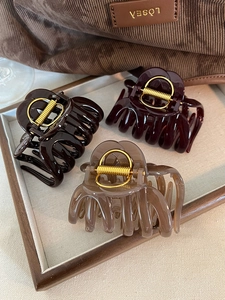 Three acrylic pumpkin stripe hair claws in brown and black on a wooden tray