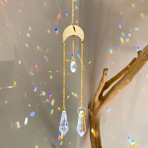 Golden crescent sun catcher with crystal prisms casting rainbow reflections on wall
