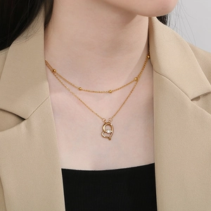 Double-layer gold heart necklace with zircon pendant worn by model on beige blazer