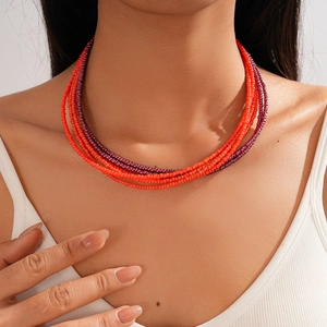 Detail of bohemian multilayer seed bead necklace in orange and purple on model