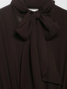 Detail of elegant oversized bow tie on dark brown chiffon dress neckline for women