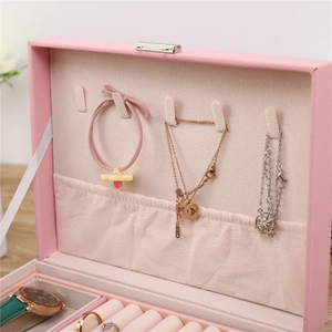 Pink leather jewelry box interior featuring ring slots and watch storage compartments